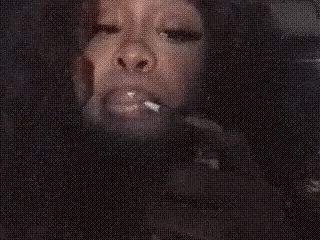 a woman is smoking a cigarette in front of a candle .