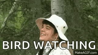 a man wearing a white hat is smiling while watching a bird .