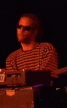 a man wearing sunglasses and a striped shirt playing drums