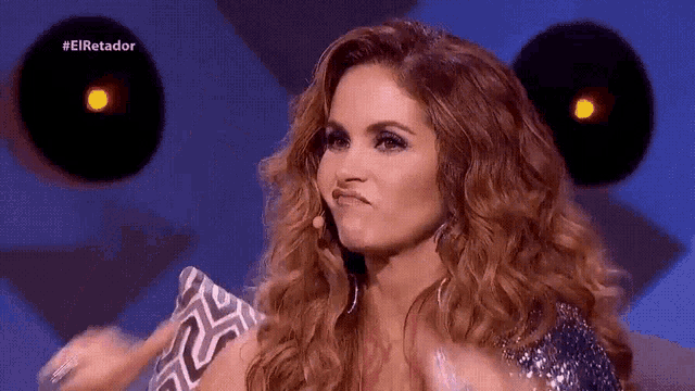 a woman is making a funny face in front of a microphone while wearing a silver dress .