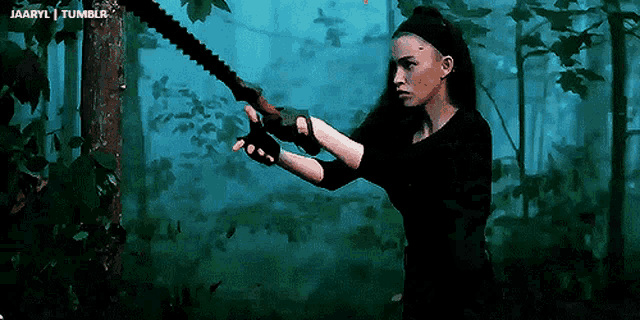 a woman is holding a large saw in a dark forest with the words jaaryl tumblr in the corner