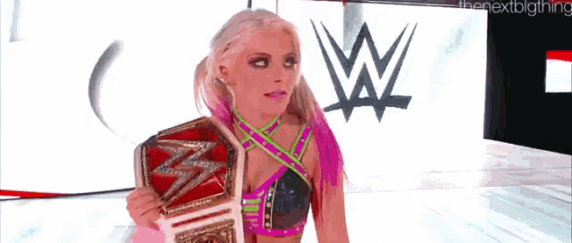 a woman is holding a wrestling championship belt in front of a wwe logo .
