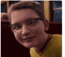 a young boy wearing glasses and a yellow shirt is smiling .
