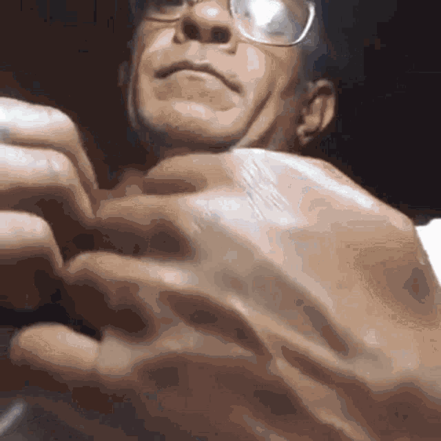 a close up of a man wearing glasses holding something in his hands
