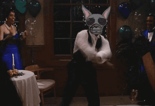 a woman in a blue dress and a man in a tuxedo are dancing in a room filled with balloons