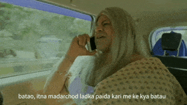 a man with long hair is talking on a cell phone