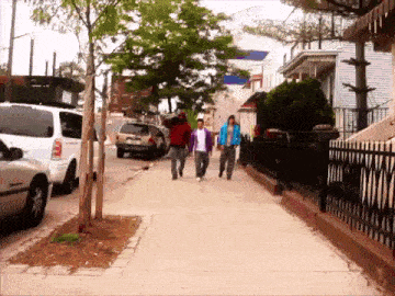 a group of people walking down a sidewalk with a white van parked on the side of the road