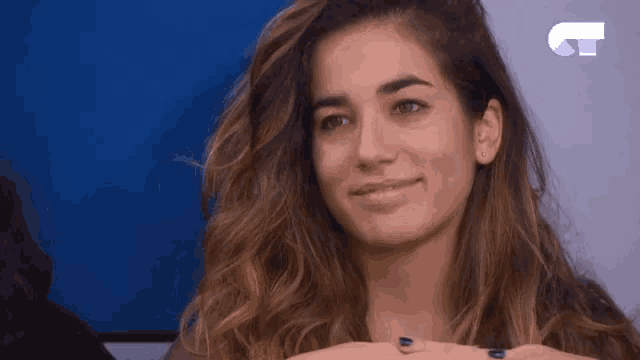 a woman with blue nails is smiling in front of a blue background