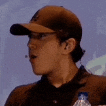 a man wearing a baseball cap and a microphone is holding a water bottle .