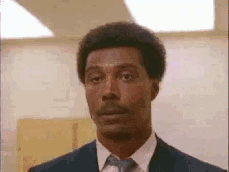 a man in a suit and tie is looking at the camera and making a funny face .
