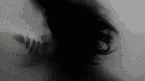 a blurry black and white photo of a woman 's face behind a glass wall .