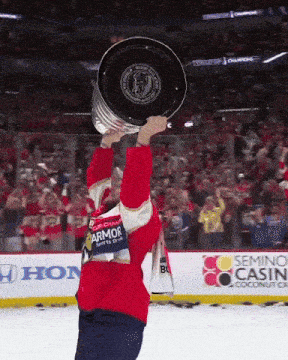 a hockey player holds up a trophy in front of a semino castle banner