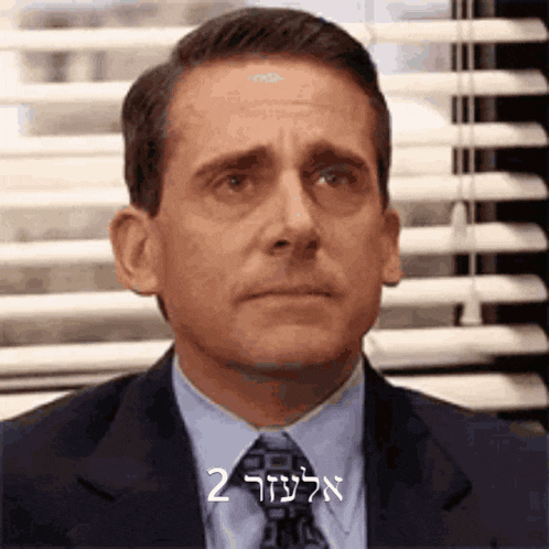 a man in a suit and tie is sitting in front of a window .