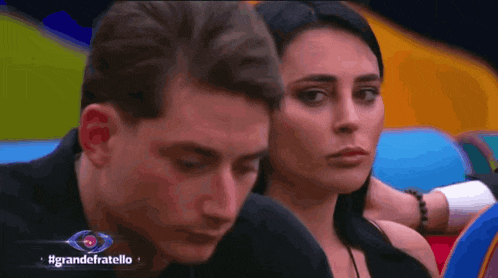 a man and a woman are sitting next to each other in a colorful room with the words grandefratello in the corner
