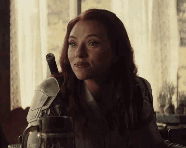 a woman with red hair is sitting at a table holding a sword