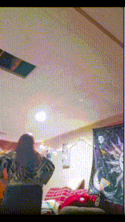 a woman in a room with a ceiling fan and a tapestry