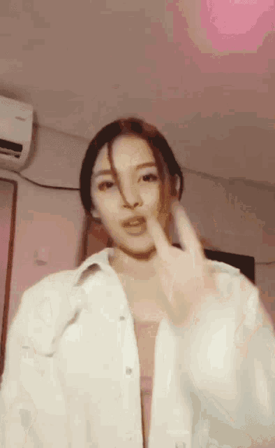 a woman in a white jacket is giving the middle finger to the camera