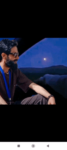 a man with a beard wearing sunglasses and a lanyard is sitting in a car .
