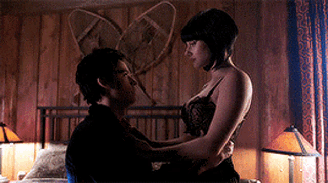 a man and a woman are kissing in a bedroom with snow shoes on the wall behind them