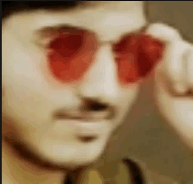 a close up of a man wearing red sunglasses with red lenses .
