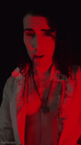 a man in a vampire costume is standing in a red light ..