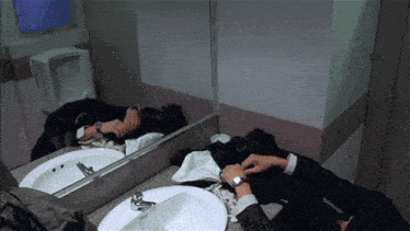 a man in a suit is laying on a bathroom counter
