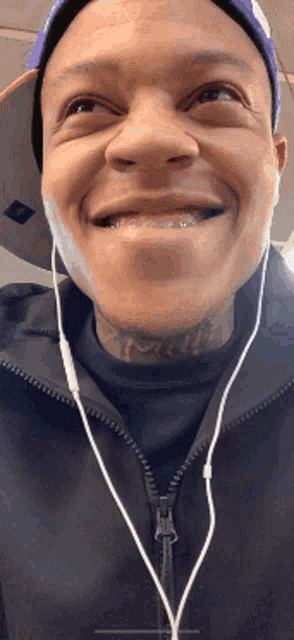 a man wearing a hat and earbuds is smiling