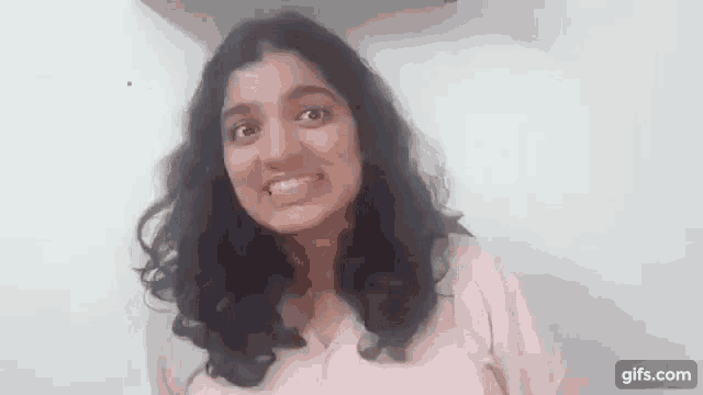 a woman with long dark hair is smiling and making a funny face .