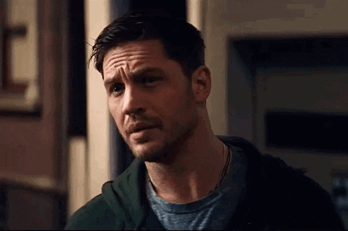 a close up of a man with a beard wearing a green hoodie and a grey t-shirt .