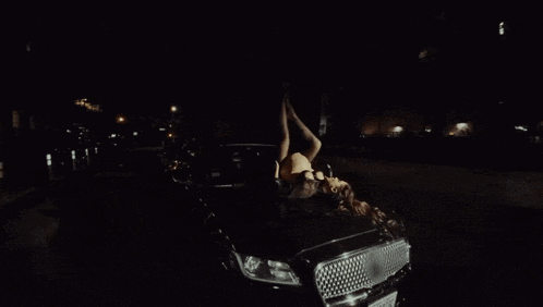 a woman is laying on her back with her legs up in the dark