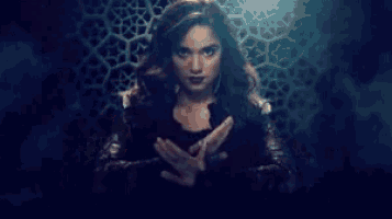 a woman is holding a glowing object in her hands in front of a dark background .
