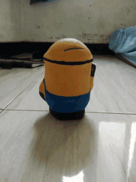 a yellow and blue minion figurine sits on a tile floor