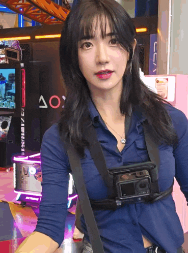 a woman in a blue shirt is holding a camera around her waist