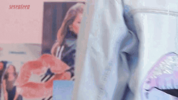 a woman in a blue shirt is standing in front of a wall with a picture of a flamingo on it .