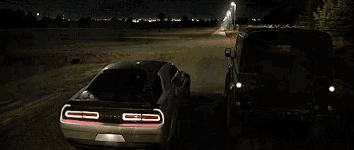 a car is being towed by a truck with a fence in the background .
