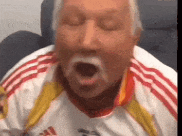 a man with a mustache and a white shirt is making a funny face .