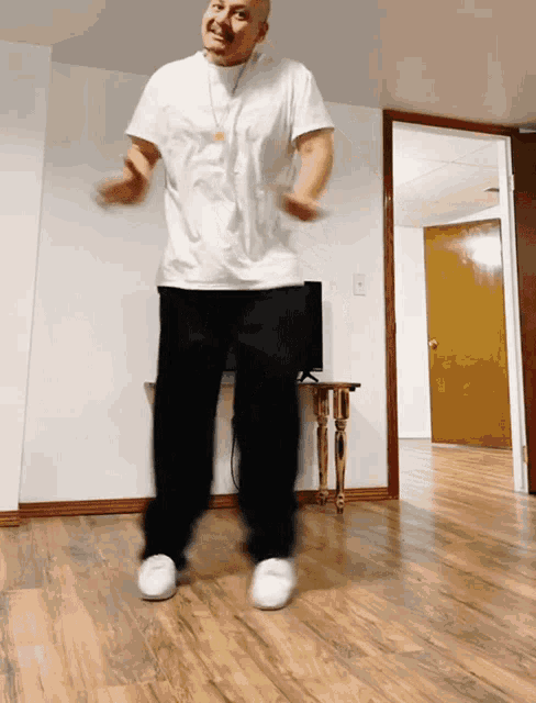 a man in a white shirt and black pants is dancing on a wooden floor