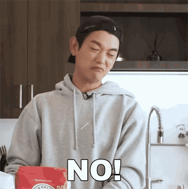a man in a grey hoodie says no in front of a bag of chips