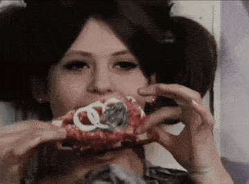 a close up of a woman eating a piece of food with a coin in her mouth