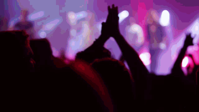 a crowd of people raising their hands in the air