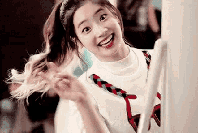 a girl is smiling and holding her hair in a ponytail while standing in front of a mirror .