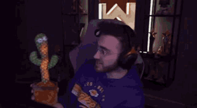 a man in a purple hoodie is holding a stuffed cactus in his hands .