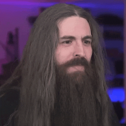a man with long hair and a beard is making a face and saying `` sounds good '' .