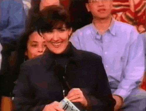 a woman is smiling while holding a piece of paper that says ' i 'm sorry ' on it