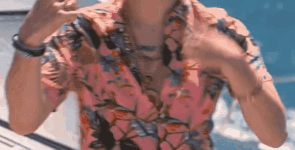 a man wearing a pink floral shirt has a tattoo on his chest that says " jesus "