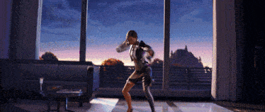 a woman is dancing in a living room with a large window