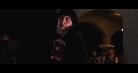 a man is standing in a dark room holding a pizza in his hand .