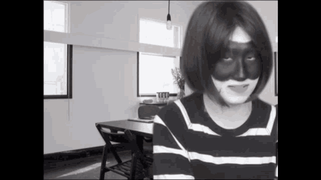 a woman wearing a black and white striped shirt with a black face paint