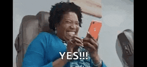 a woman is sitting in a chair looking at her cell phone .