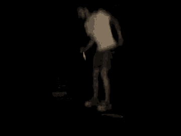 a man is standing on a skateboard in the dark holding a knife .